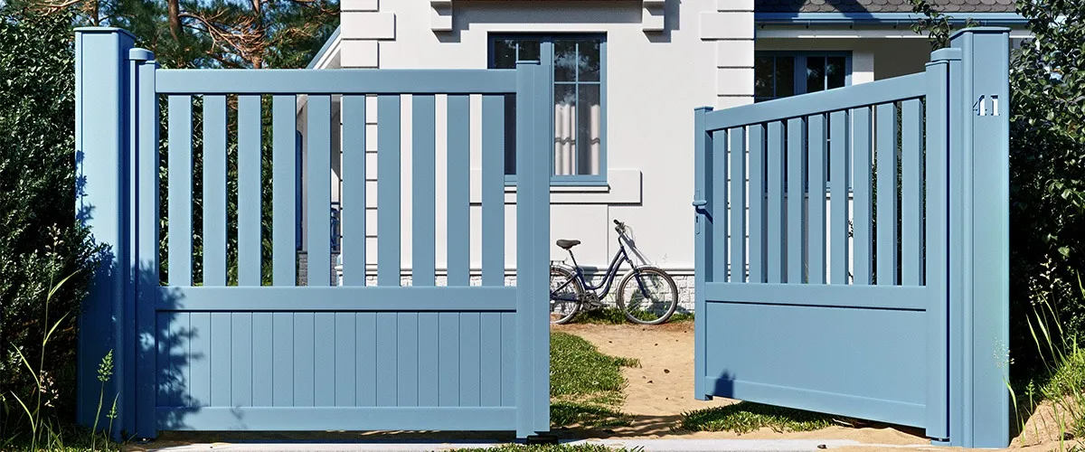 Portail battant en aluminium bleu-gris à barreaudage ouvert devant une maison